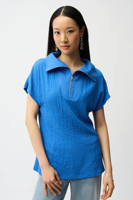 Woman wearing Joseph Ribkoff seersucker boxy top with memory collar, featuring a textured fabric, zip neckline, short sleeves, and a relaxed modern fit.