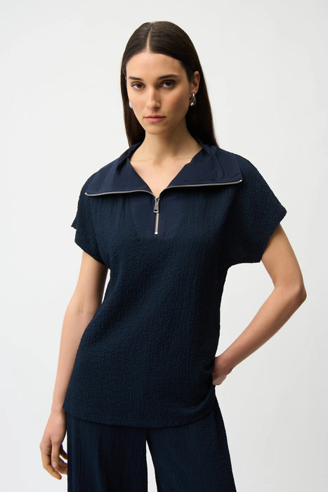 Woman wearing a navy blue zip front short sleeve top from Joseph Ribkoff