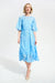 Woman wearing a light blue midi dress with 3D floral details and waist sash from Joseph Ribkoff