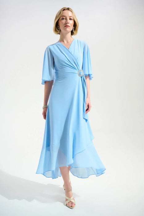 Woman wearing a light blue dress with wrap neck and ruffle hem from Joseph Ribkoff