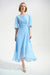 Woman wearing a light blue dress with wrap neck and ruffle hem from Joseph Ribkoff