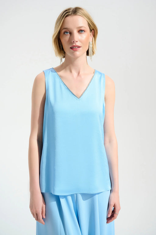 Woman wearing a light blue sleeveless top with rhinestone trim v-neck from Joseph Ribkoff
