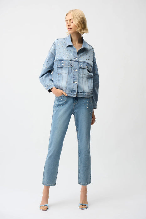 Woman wearing Joseph Ribkoff slim leg jeans with pearls and studs, featuring embellished light-wash denim, cropped length, and a flattering modern fit.