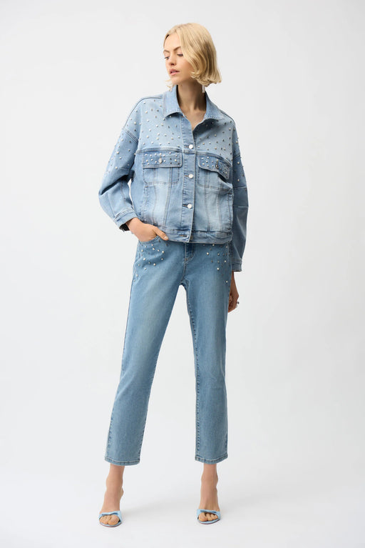 Woman wearing Joseph Ribkoff slim leg jeans with pearls and studs, featuring embellished light-wash denim, cropped length, and a flattering modern fit.