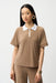 Woman wearing a silky knit boxy polo top with contrast white collar and gold zipper, styled for office wear, travel, or modern casual chic outfits.