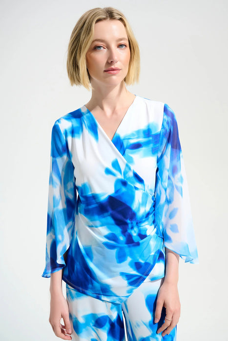 Woman wearing a blue and white floral print wrap top with 3/4 sleeves from Joseph Ribkoff