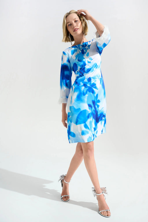 Woman wearing a white and blue floral knee-length shift dress with 3/4 sleeves and fringe cuffs from Joseph Ribkoff