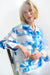 Woman wearing a blue and white jacket with alternating floral print and shadow stripes from Joseph Ribkoff