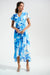 Woman wearing a blue floral wrap dress with high low ruffle hem from Joseph Ribkoff