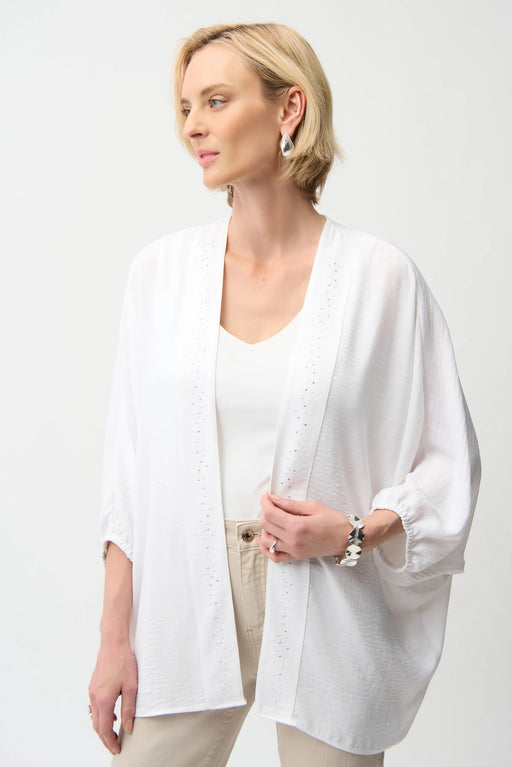Woman wearing a white open front cover-up with rhinestone embellishments and 3/4 sleeves from Joseph Ribkoff