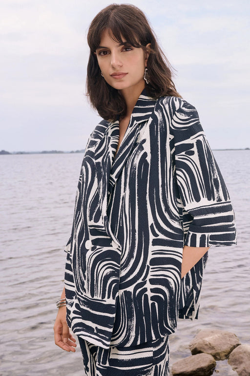 Woman wearing a vanilla and midnight blue abstract double-breasted blazer with a relaxed tailored fit, styled for a chic and modern statement look.