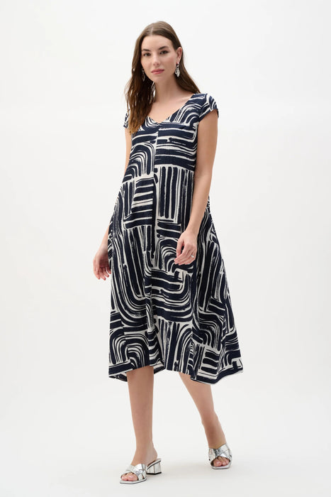 Woman wearing a vanilla and midnight blue abstract print cocoon midi dress with cap sleeves and V-neckline, styled for a modern chic look