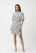 Woman wearing Joseph Ribkoff dot print A-line shirt dress with puff sleeves and button-down front, showcasing a feminine and modern silhouette.
