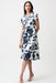Model wearing Joseph Ribkoff vanilla and midnight blue floral print fit and flare shirt dress with short sleeves and belted waist for an elegant feminine silhouette.