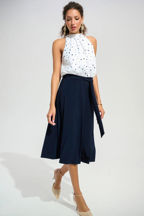 Woman wearing a halter midi dress with white polka dot blouson bodice and navy blue skirt from Joseph Ribkoff
