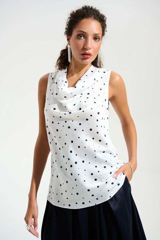 Woman wearing a white sleeveless top with dark blue polka dots and cowl neck from Joseph Ribkoff