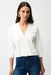 Woman wearing a white cropped v-neck cardigan with mirrored grommet accents from Joseph Ribkoff