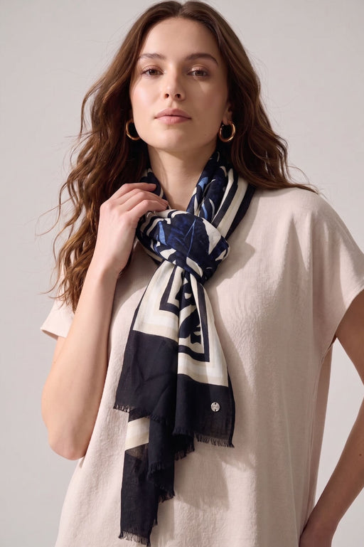 Woman wearing an abstract printed scarf with solid border and fringe edges from Joseph Ribkoff