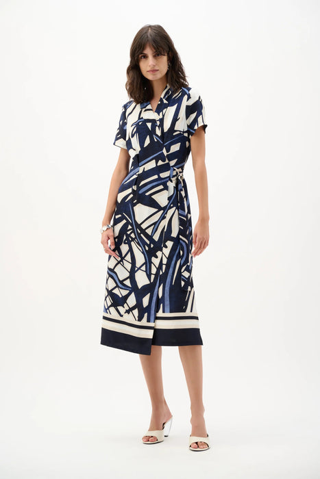 Woman wearing a navy and vanilla abstract print shirt dress with a belted waist and midi length, styled for a modern and polished look