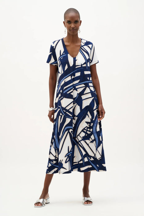 Woman wearing a vanilla and multi abstract print trapeze midi dress with V-neckline and short sleeves, styled for a relaxed modern summer look