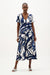 Woman wearing a vanilla and multi abstract print trapeze midi dress with V-neckline and short sleeves, styled for a relaxed modern summer look
