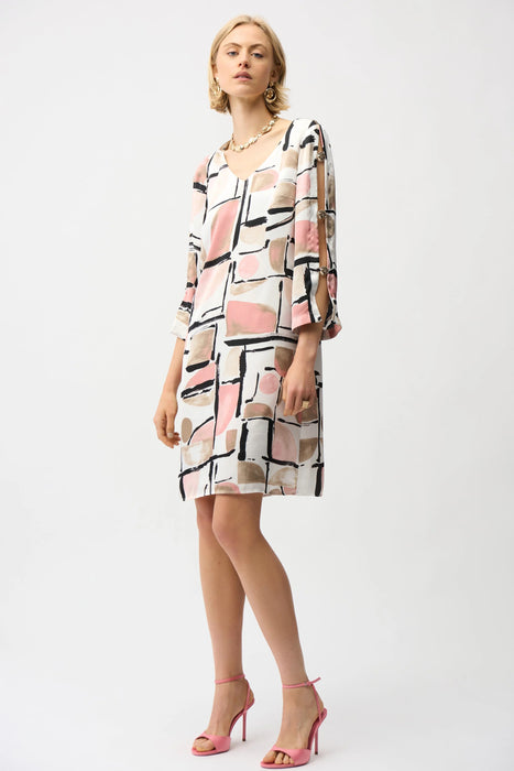 Woman wearing Joseph Ribkoff abstract print trapeze dress with gold neckline detail, featuring a flowy silhouette and elegant modern style.