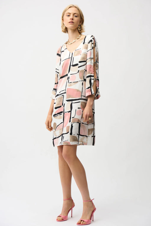 Woman wearing Joseph Ribkoff abstract print trapeze dress with gold neckline detail, featuring a flowy silhouette and elegant modern style.