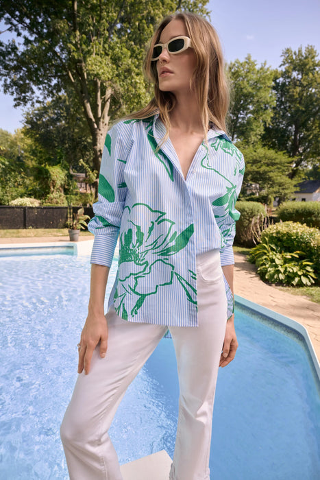 Woman wearing Joseph Ribkoff cotton stripe floral print boxy blouse, featuring lightweight breathable fabric, relaxed fit, bold green floral design, and chic casual styling paired with white pants.