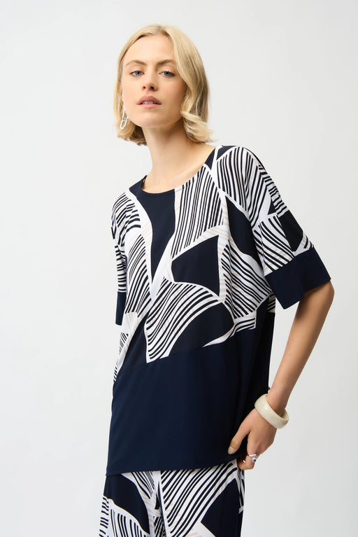 Woman wearing a geometric patterned short sleeve top with scoop neck and asymmetric hem from Joseph Ribkoff
