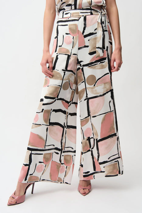 Woman wearing a geometric-patterned wide leg pants with waist sash from Joseph Ribkoff