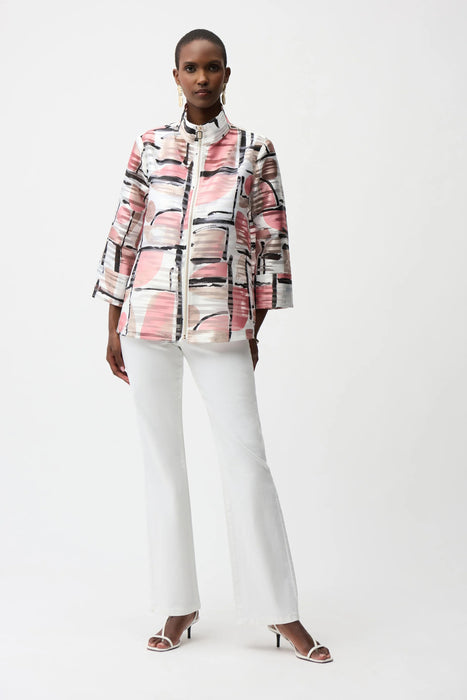 Woman wearing a lightweight organza abstract print boxy jacket with zip front and three-quarter sleeves, paired with white pants and heels.