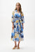 Woman wearing a Joseph Ribkoff vanilla multi tropical print A-line wrap midi dress with tie waist and relaxed sleeves, styled for a chic summer look
