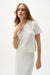 Woman wearing Joseph Ribkoff vanilla textured sweater knit short sleeve shirt, featuring a polo collar, button detail, soft knit fabric, and a relaxed elegant fit.
