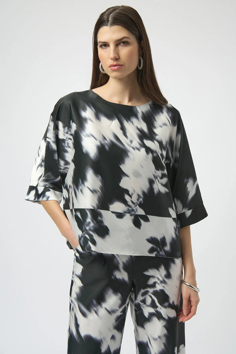 Woman wearing a black and floral patterned satin top with 3/4 sleeves