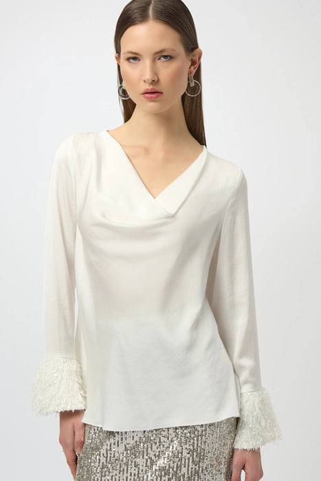 Woman wearing a white satin blouse with cowl neck and fringe cuffs