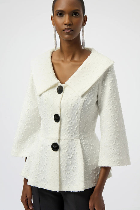 Woman wearing a white textured, sequined bouclé peplum jacket with black buttons and 3/4 sleeves