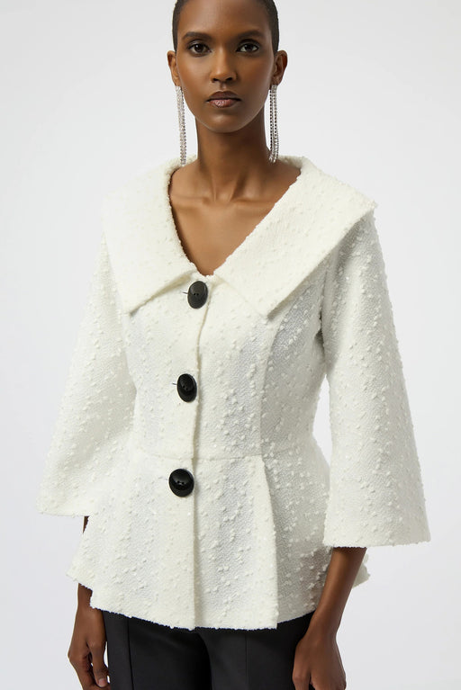 Woman wearing a white textured, sequined bouclé peplum jacket with black buttons and 3/4 sleeves
