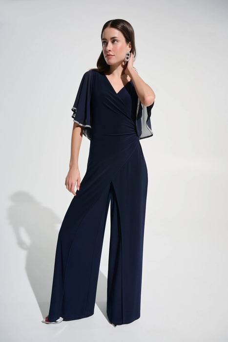 Woman wearing a wrap rhinestone trim wide leg jumpsuit featuring flutter sleeves and an elegant flowing silhouette
