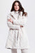 A woman wearing a plush, quilted faux fur coat in a light cream or off-white color from Nikki Jones
