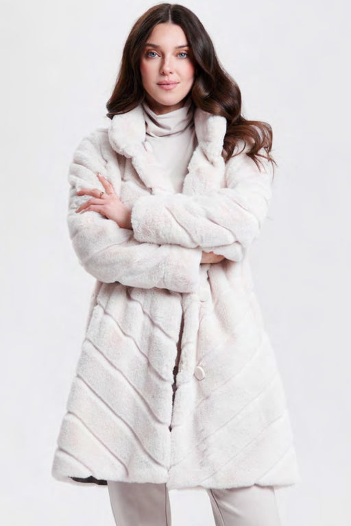 A woman wearing a plush, quilted faux fur coat in a light cream or off-white color from Nikki Jones