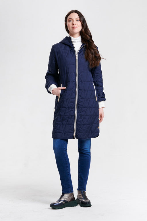 A woman modeling a navy blue quilted hooded puffer coat with a silver zipper closure and zip pockets from Nikki Jones