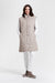 A woman modeling a taupe-colored quilted mid-length coat with a high collar convertible to a vest from Nikki Jones
