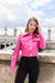 Woman wearing a hot pink patent leather crop jacket with gold buttons with long sleeves and pockets from OO LA LA