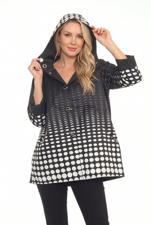 Woman wearing the Oopera Black Polka Dot Reversible Toggle Raincoat with a black and white ombre pattern, adjustable hood, and loose-fitting silhouette.