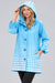 Woman wearing the Oopera Light Blue Polka Dot Reversible Toggle Raincoat with a sky-blue and white ombre pattern, attached hood, and flowing A-line silhouette.