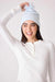 Woman wearing a light blue soft chenille cable knit beanie with faux fur pom pom at the top