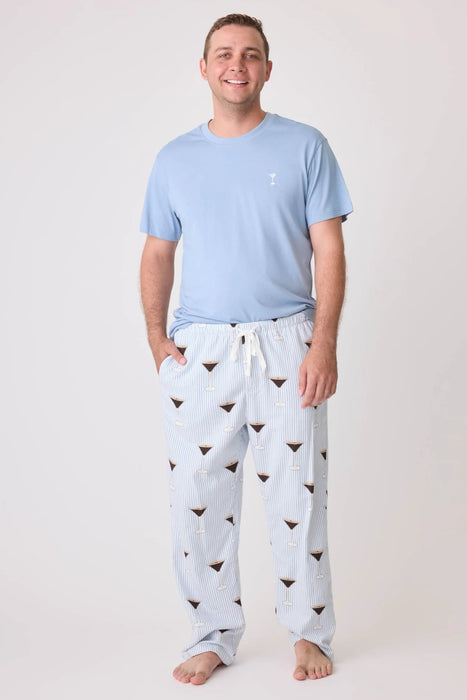 Man wearing a pajama set consisting of a light blue top and striped pajama pant with espresso martini print
