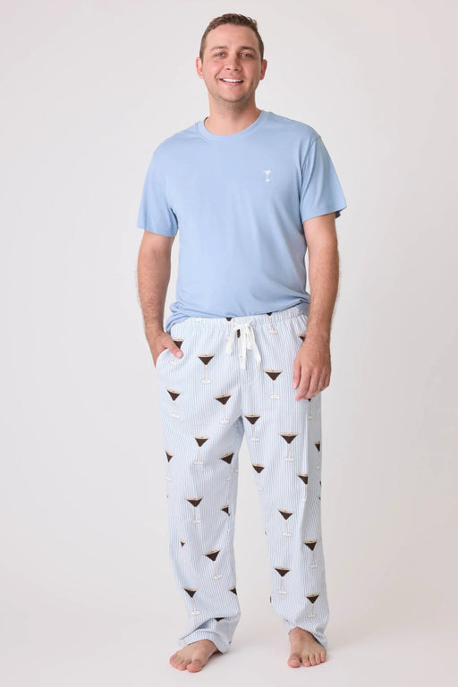 Man wearing a pajama set consisting of a light blue top and striped pajama pant with espresso martini print