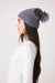 Woman wearing a gray soft chenille cable knit beanie with faux fur pom pom at the top