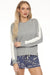 Woman wearing a gray pullover lounge top with cable knit insert at the sleeves